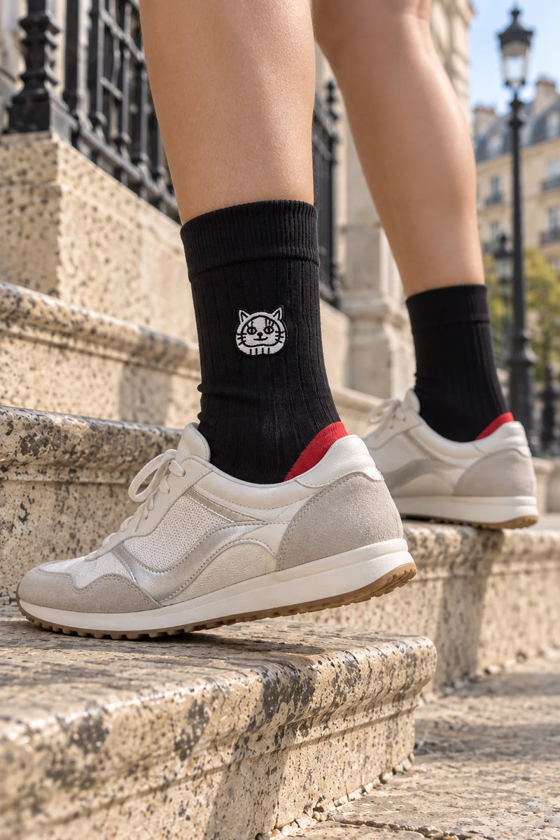 Black LukyNeko lucky socks with red sole worn on the steps of Paris